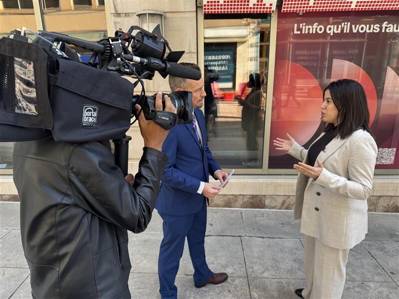 Une femme en entrevue à l'extérieur, parlant à un journaliste pendant qu'un caméraman filme la scène.